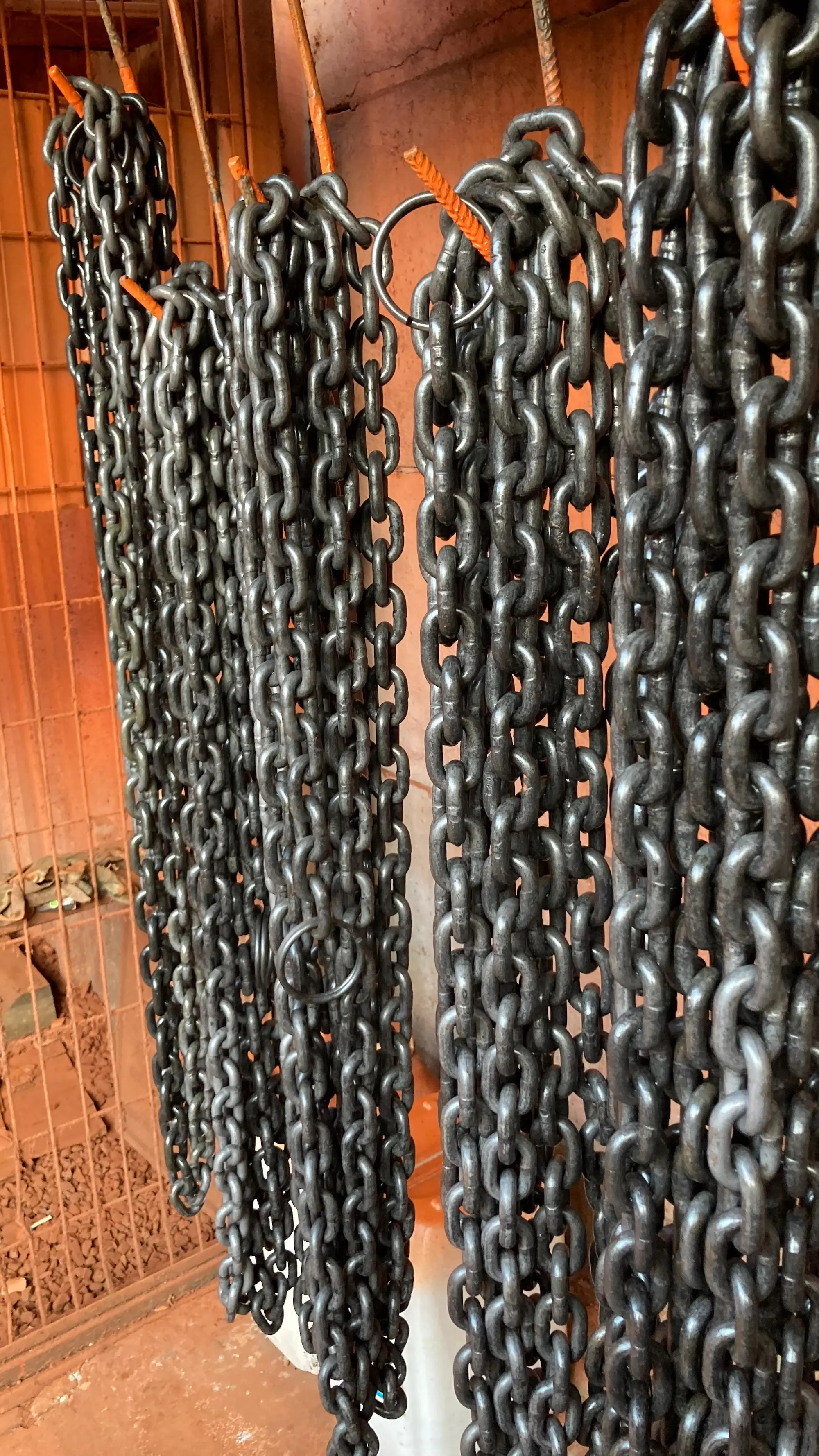 Cadenas de acero industriales colgadas en fila, utilizadas para tecles o polipastos, listas para instalación o mantenimiento